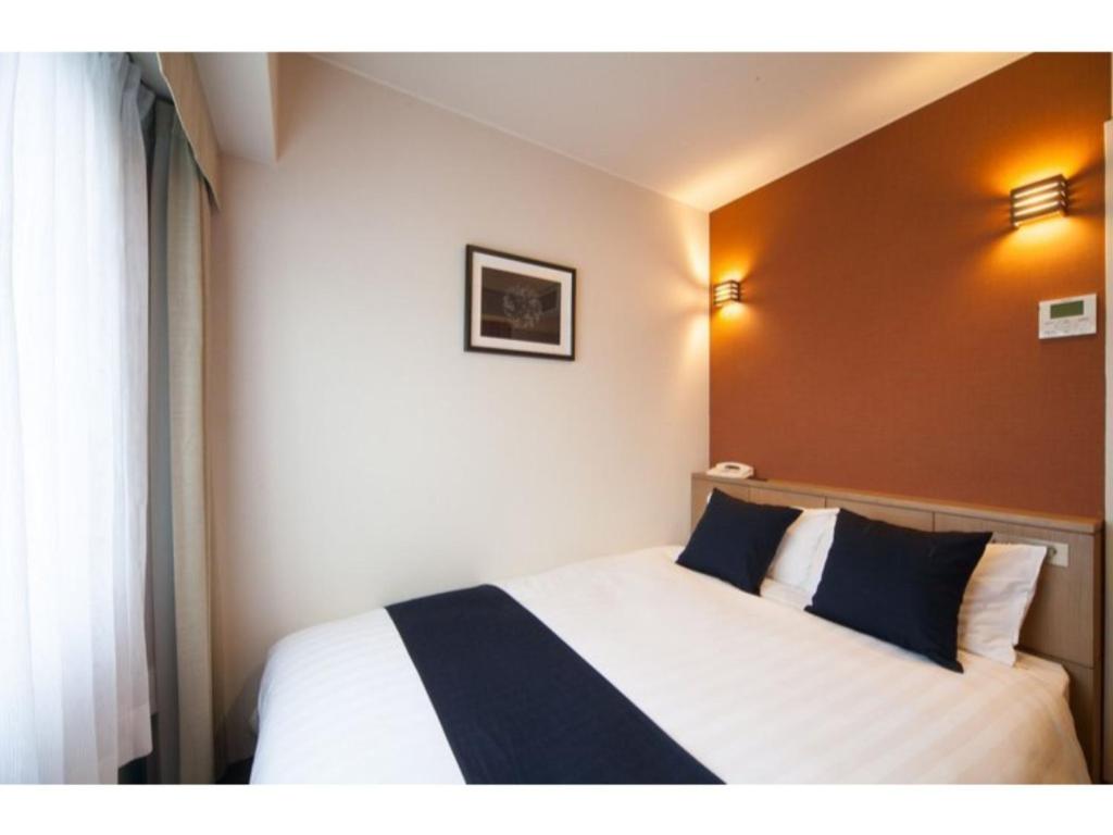 ein Hotelzimmer mit einem Bett mit blauen und weißen Kissen in der Unterkunft Hotel St Palace Kurayoshi - Vacation STAY 82276 in Kurayoshi
