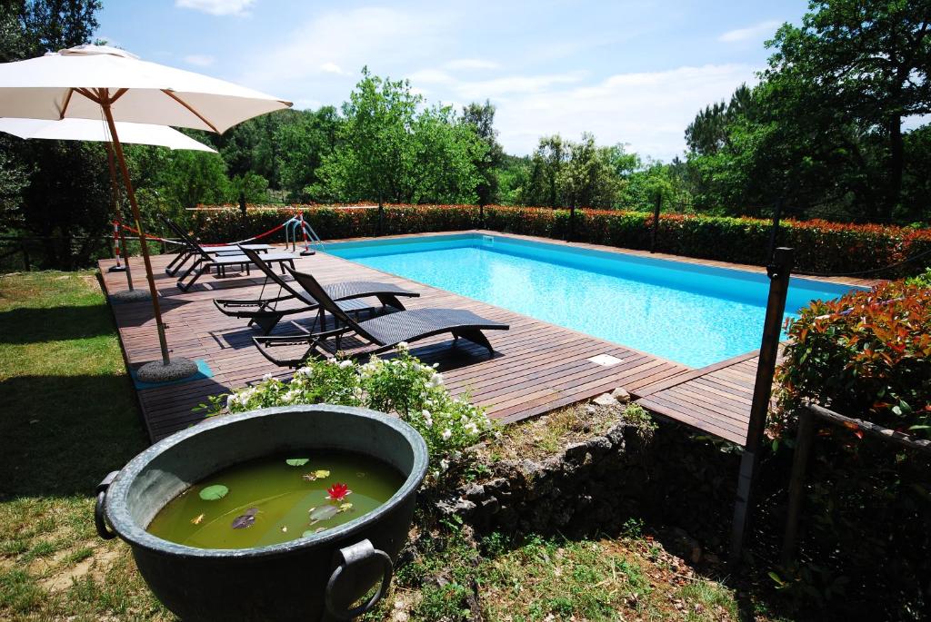 a pool with a wooden deck with a bath tub and an umbrella at Borgo dei Fondi in Siena