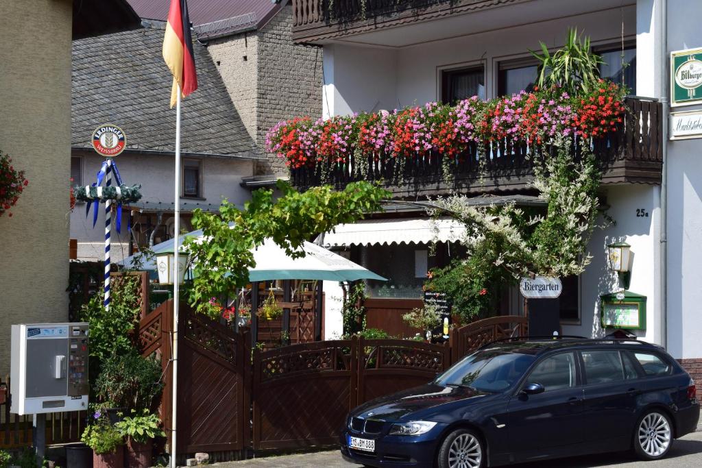 ein schwarzes Auto, das vor einem Gebäude mit Blumen parkt in der Unterkunft Gaststätte Marktstübchen in Bornich