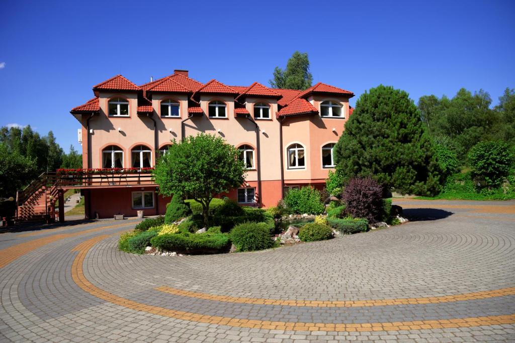 une grande maison avec une route devant elle dans l'établissement Zajazd u Hermanów, à Olsztyn