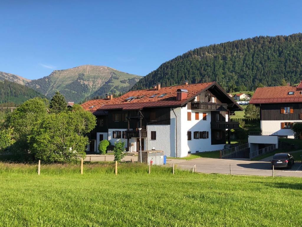 a house with a green field and mountains in the background at Ferienwohnung Steibis / Allgäu in Steibis