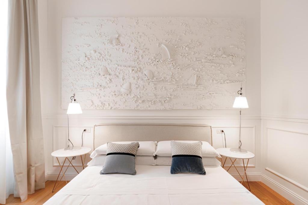 a bedroom with a white bed with two tables at PLEY Boutique Del Centro in Cagliari