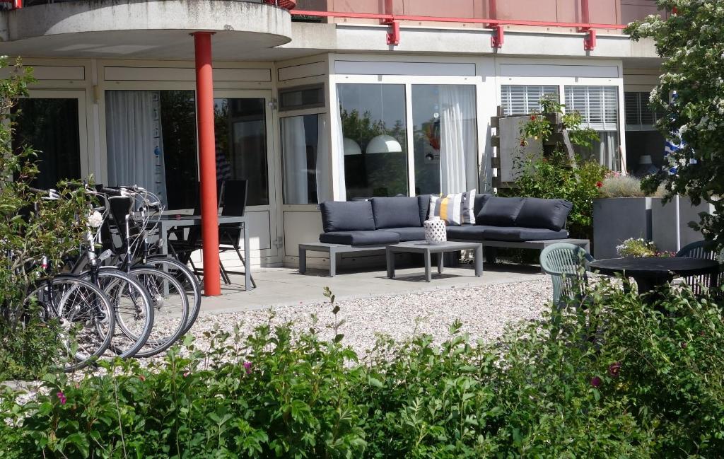 een patio met een bank en een tafel en stoelen bij Duinzicht in Buren