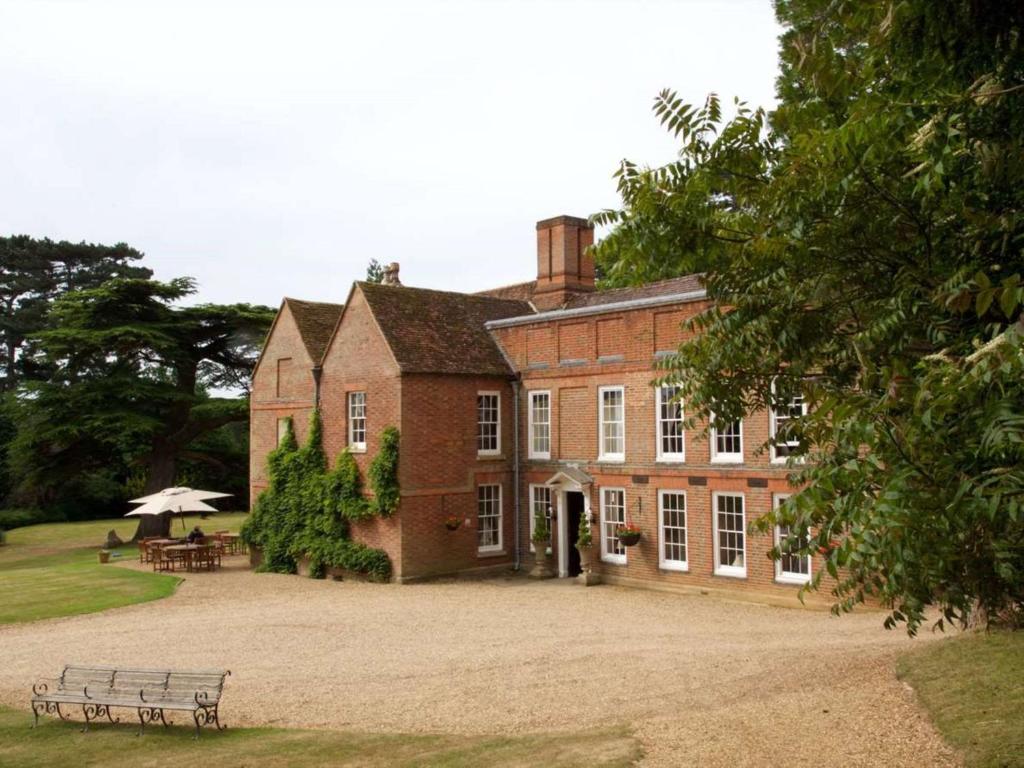 um grande edifício de tijolos com um banco em frente em Flitwick Manor Hotel, BW Premier Collection em Flitwick