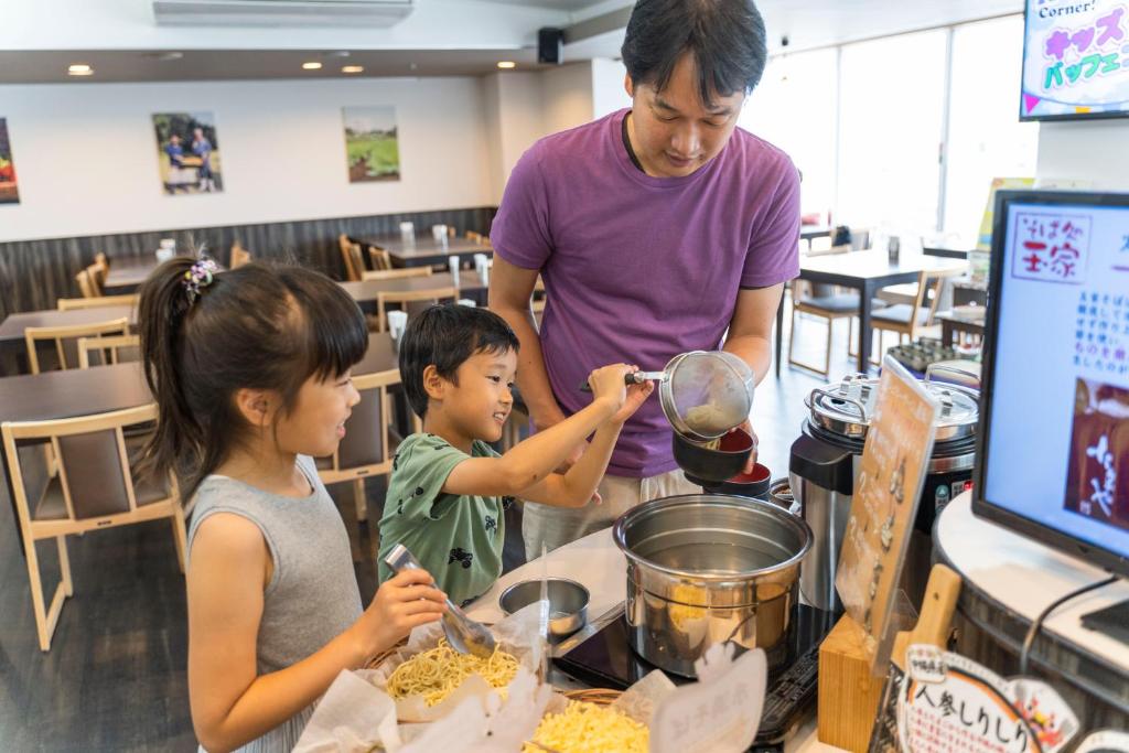 a man and two children preparing food in a restaurant at Hotel Ocean (Kokusai-Dori) in Naha