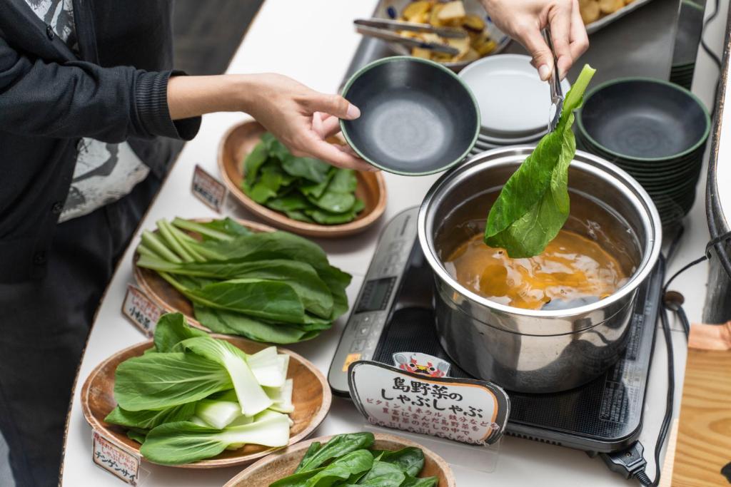a person cooking food in a pot on a stove at Hotel Ocean (Kokusai-Dori) in Naha