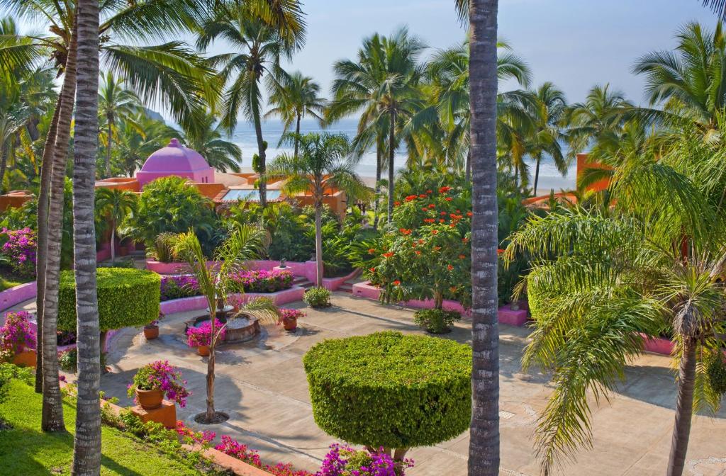 un jardin avec des palmiers et des fleurs dans un complexe dans l'établissement Las Alamandas, à Quemaro