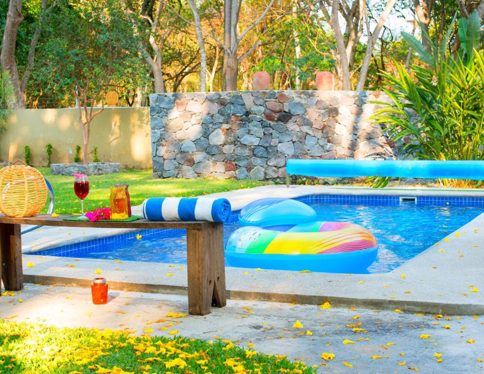 um banco de madeira com um macarrão de piscina ao lado de uma piscina em Htl & Villas Comala, alberca , parking, céntricas, Petfriendly em Comala