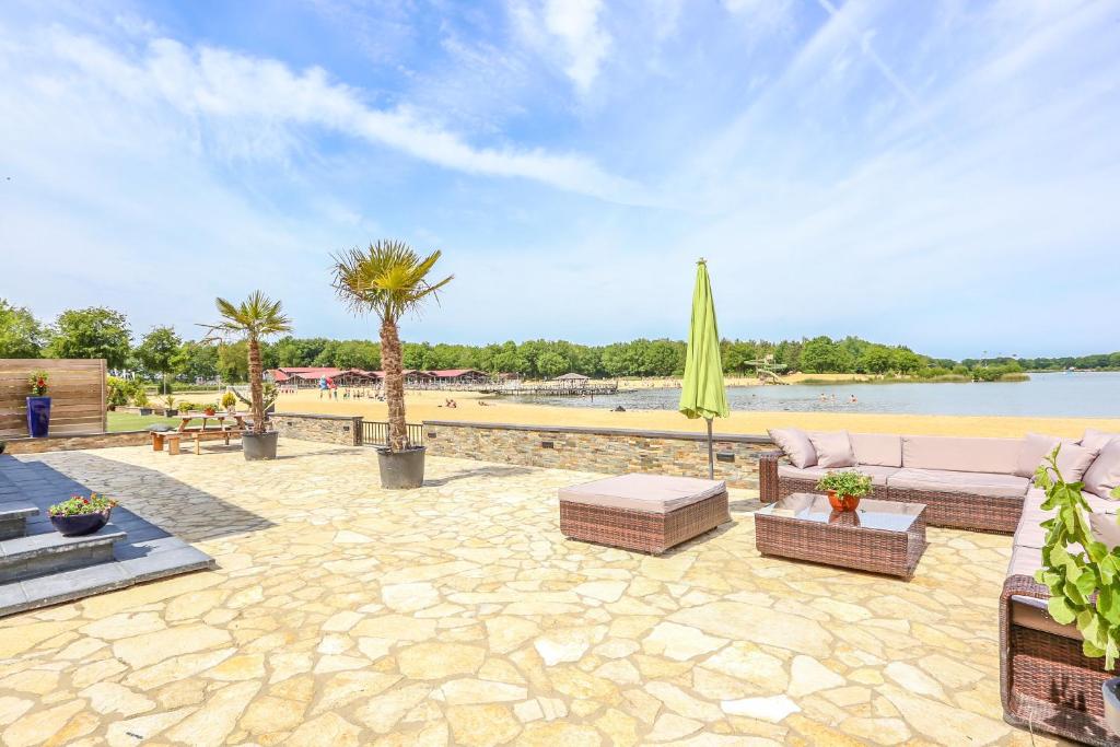 eine Terrasse mit einem Sofa, einem Sonnenschirm und einem Strand in der Unterkunft Beach house in Erm