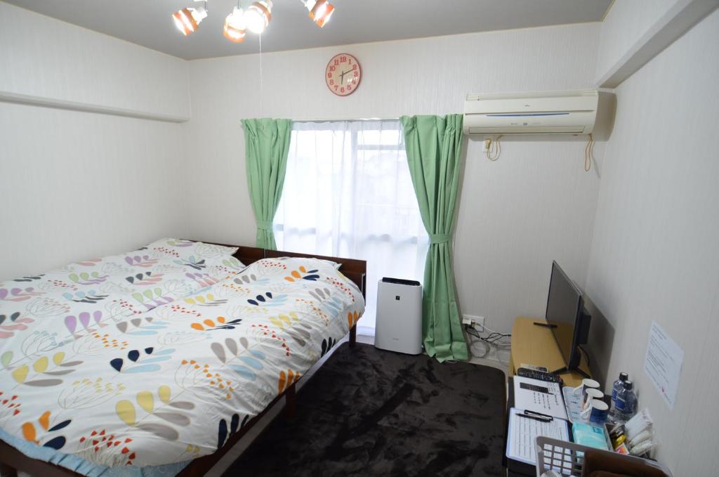 um quarto com uma cama, uma televisão e uma janela em Comfort CUBE PHOENIX MIYAZAKI em Miyazaki