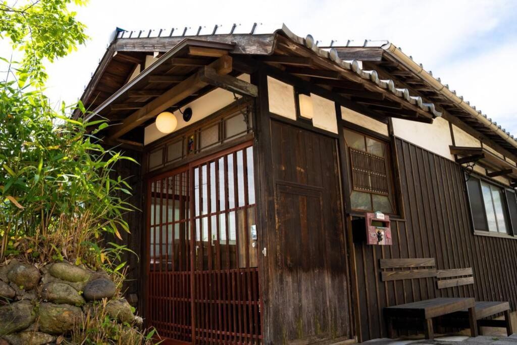 a small house with a wooden door and a gate at 鞆猫庵 Tomo Nyahn in Fukuyama