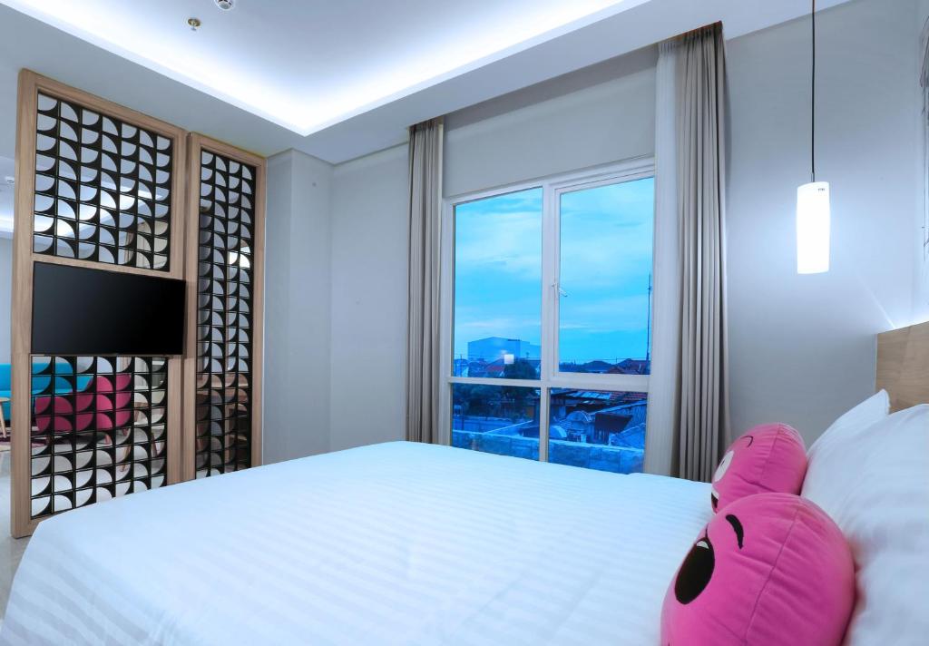 a bedroom with a large bed with a large window at favehotel Sidoarjo in Sidoarjo