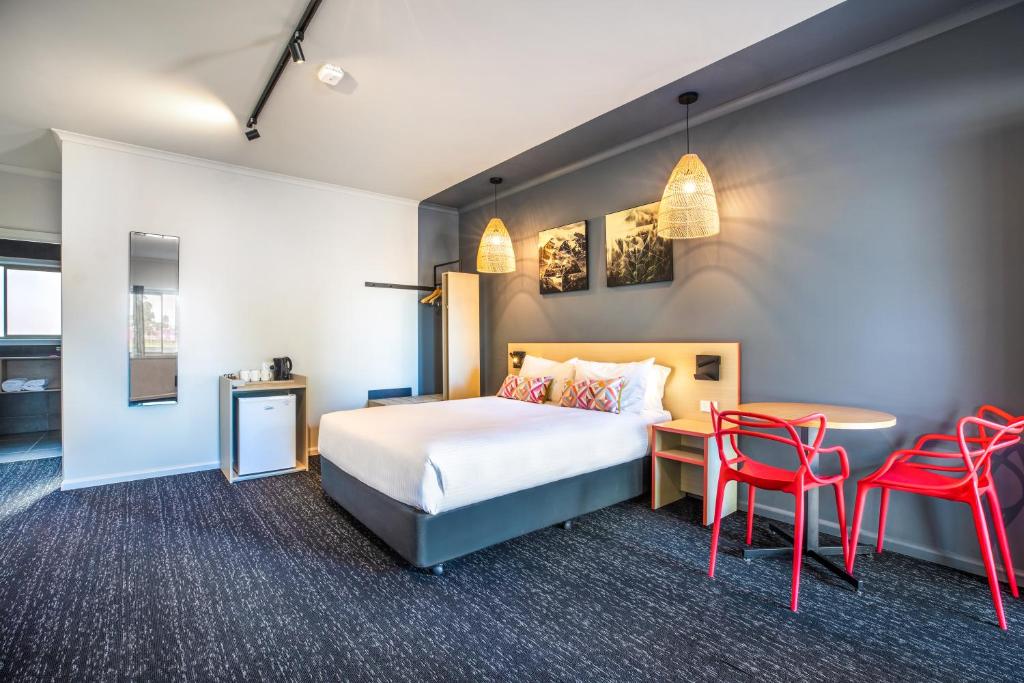 una camera d'albergo con letto, tavolo e sedie di Nightcap at Monash Hotel a Clayton North