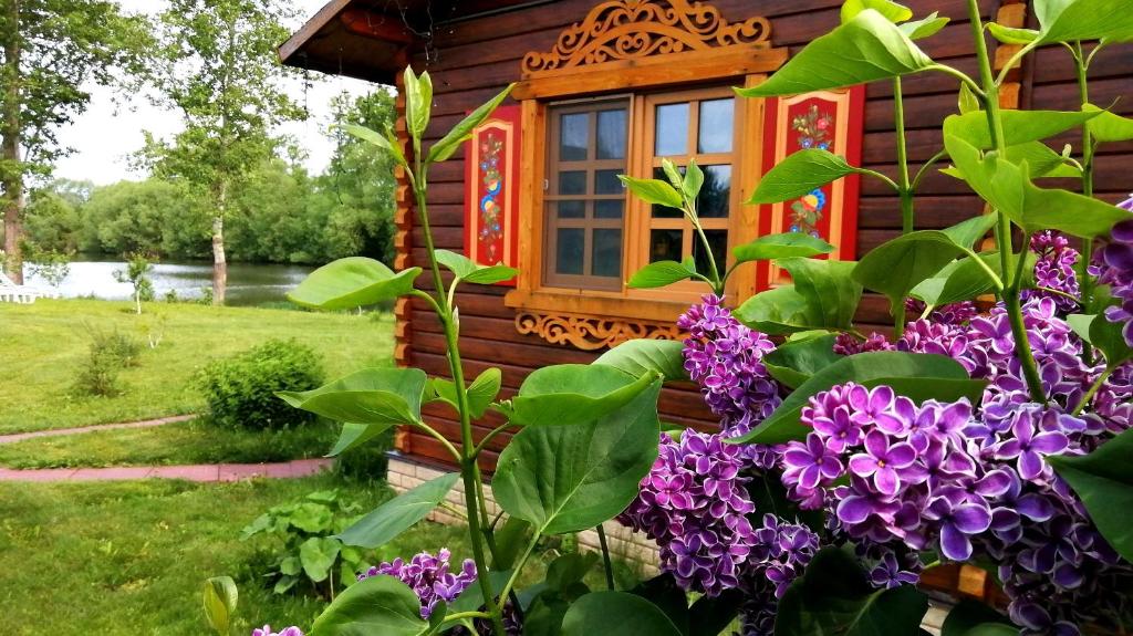 ジヴェエヴォにあるPark Hotel Divny Dvorikの紫色の花が目の前に咲く丸太小屋