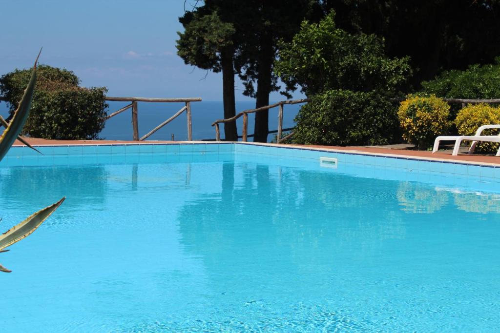 a large blue swimming pool with two white chairs at casa vacanze marzano in Tropea