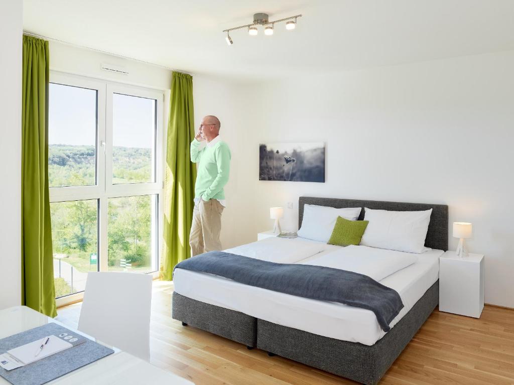 a man talking on a cell phone in a bedroom at Aparthotel Parkallee in Mainz