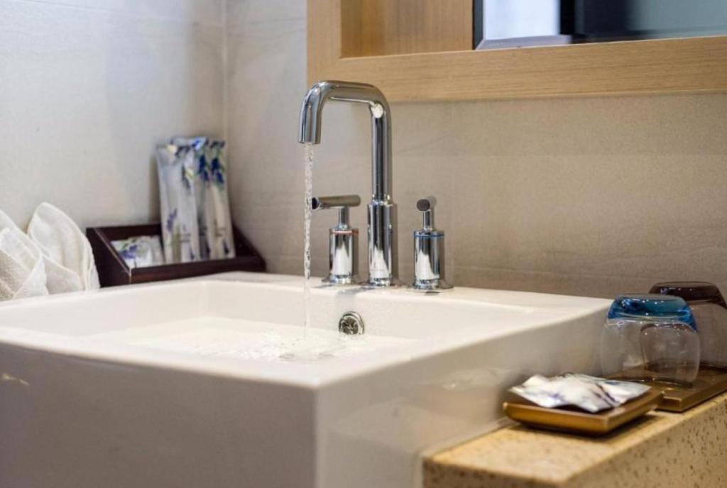 a sink with a faucet with water coming out at 7Days Premium Xiamen Airport Xianglu Branch in Xiamen