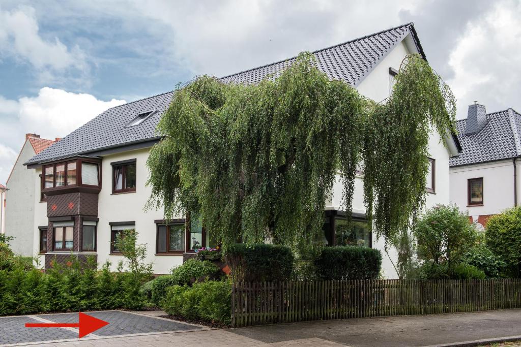 a tree in front of a white house with a red arrow at Stadtoase in Bremerhaven