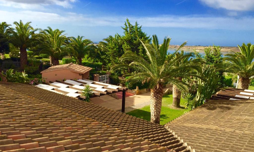 - une vue sur un complexe avec des palmiers et des bancs dans l'établissement Hotel I Ginepri, à Quartucciu