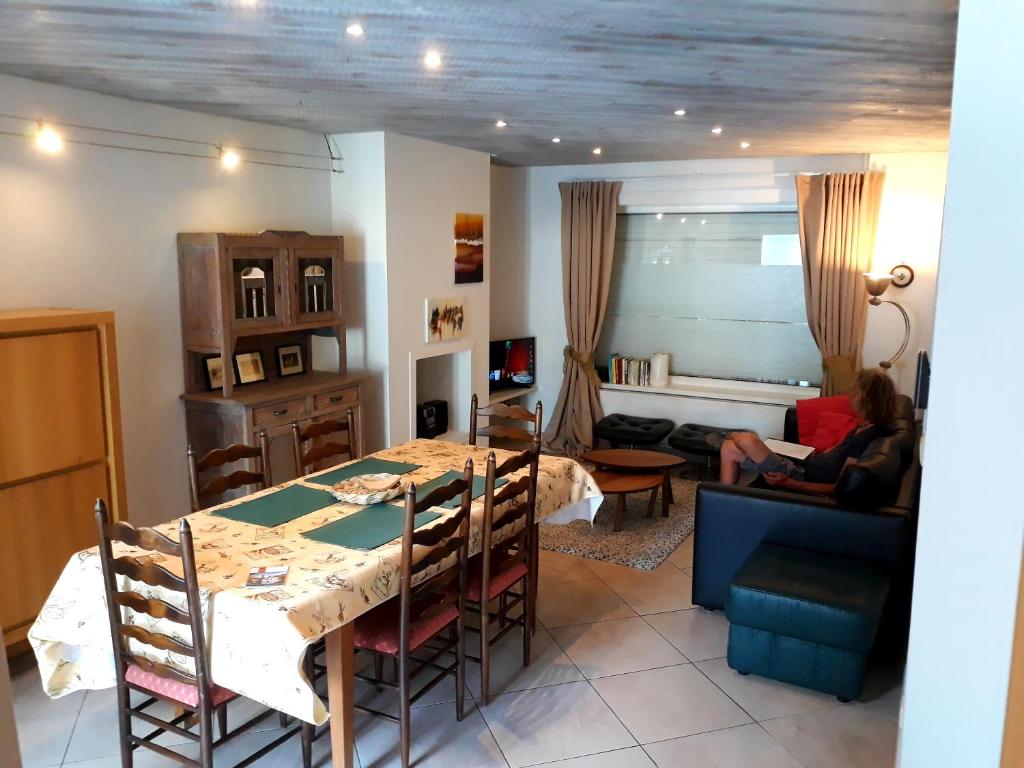 een woonkamer met een tafel en een persoon op een bank bij Vakantiewoning FINE FLEUR in Brugge