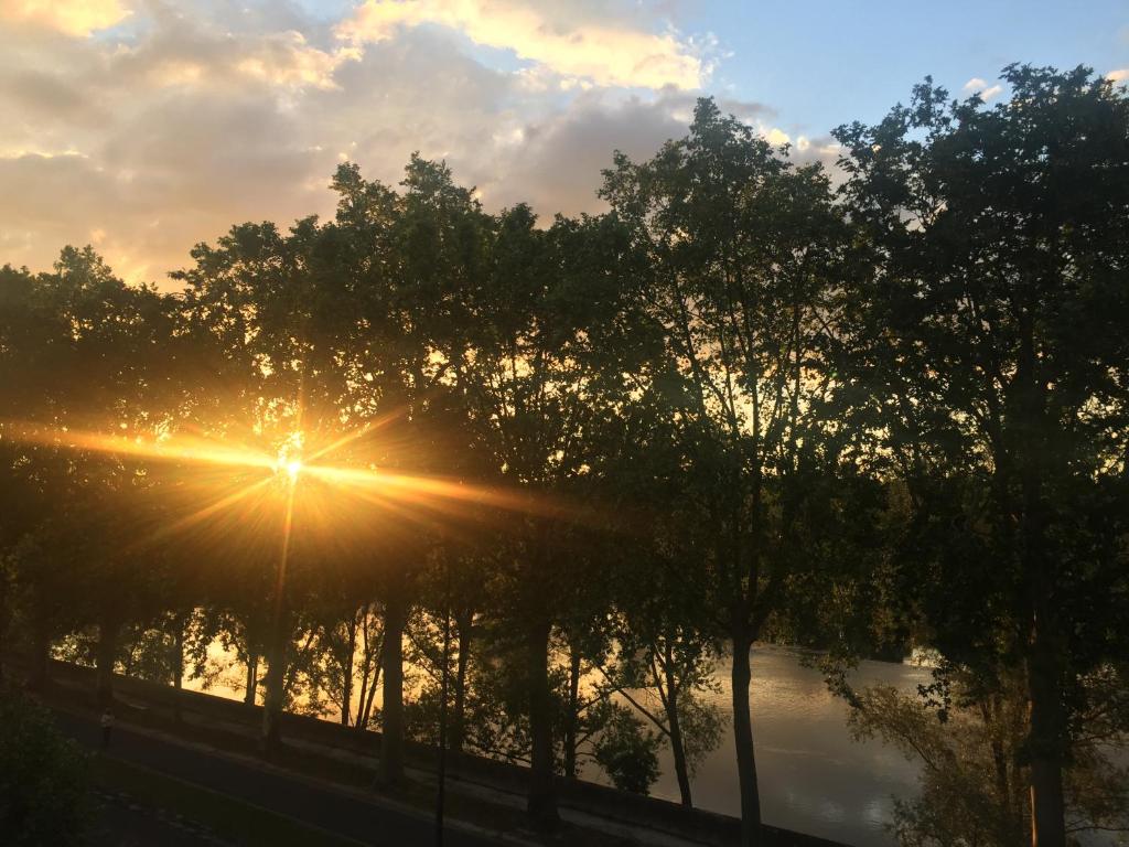 een zonsondergang boven een rivier met bomen op de voorgrond bij Loire Terrasse in Tours