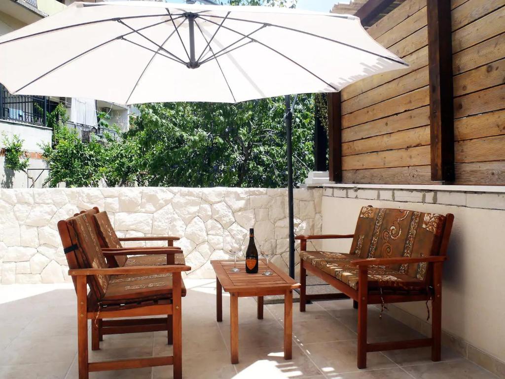 a white umbrella and two chairs and a bottle on a table at Apartment Ella in Split