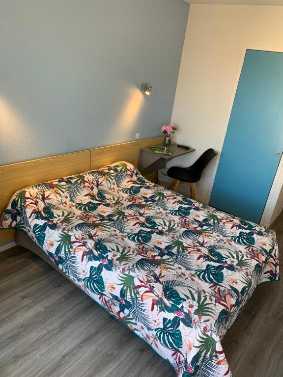 1 dormitorio con 1 cama con colcha de flores en Hotel Bains Sarrailh, en Dax