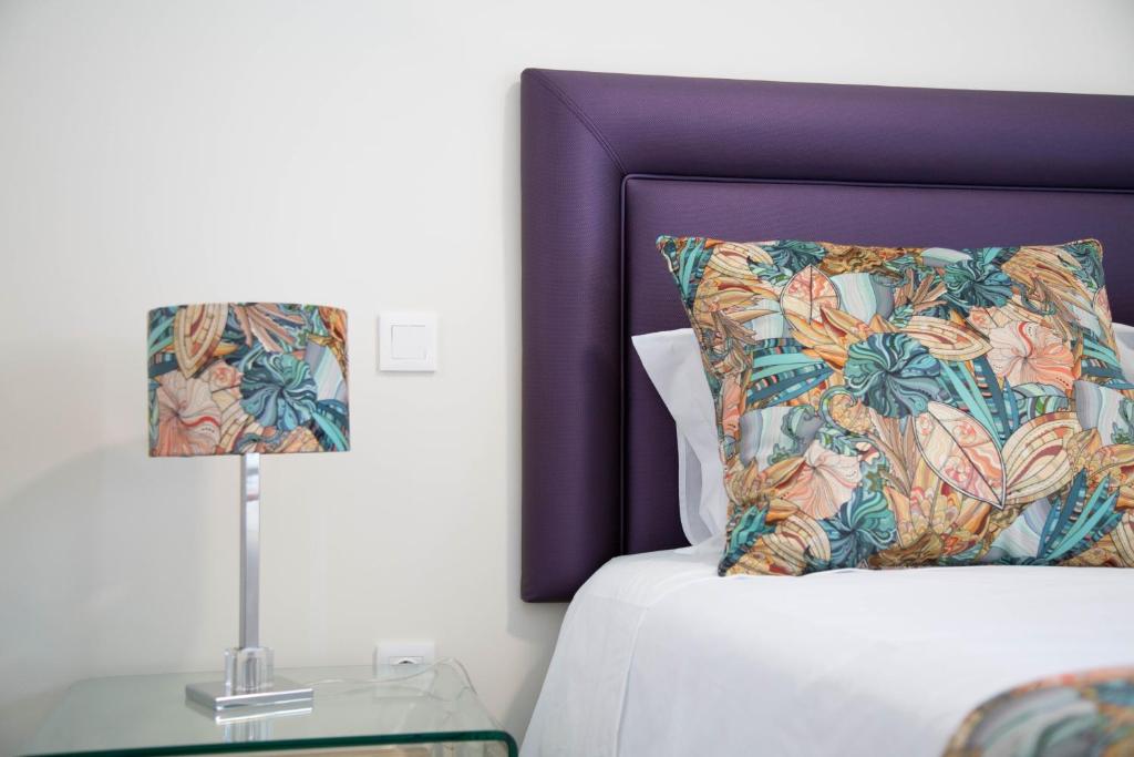 1 cama con cabecero púrpura y una lámpara sobre una mesa de cristal en Tomás Guest House, en Covilhã