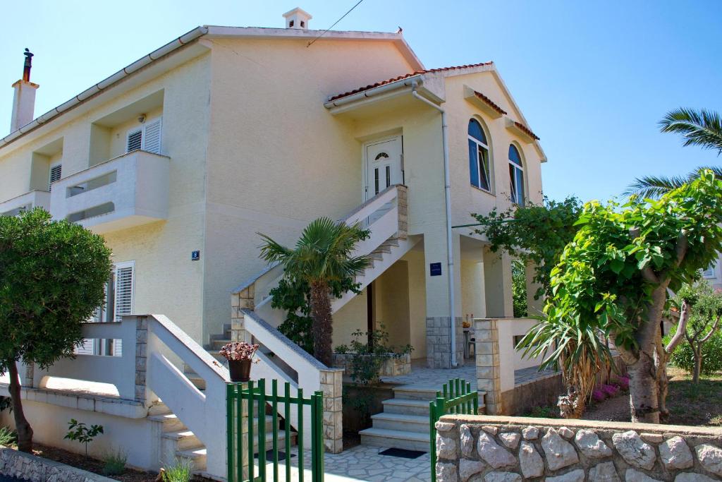 Biały dom z bramą przed nim w obiekcie Two bedroom apartments Elvira w Novalji