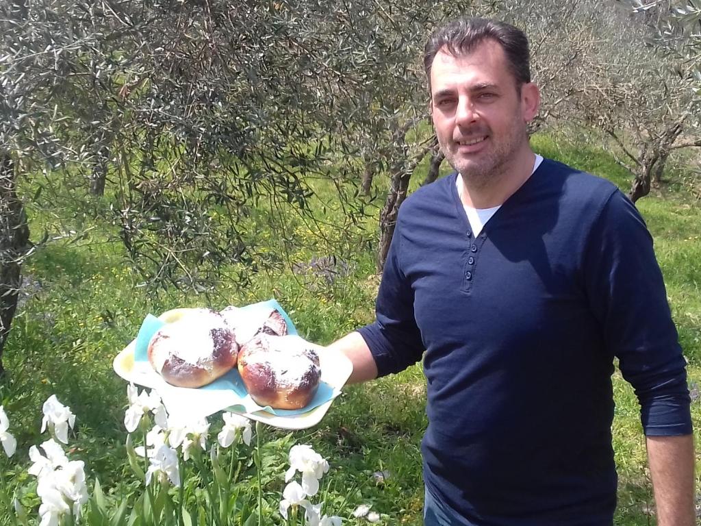 un hombre sosteniendo una bandeja de pasteles en un plato en Casa Allorello, en Laureana Cilento
