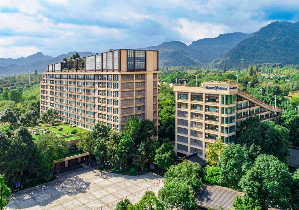 都江堰都江堰青城豪生国际酒店的以群山为背景的建筑物的鸟瞰图