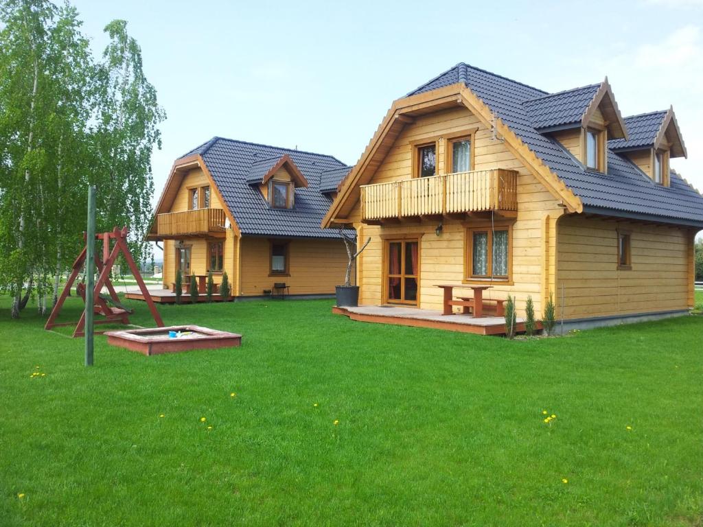 uma casa de madeira com um parque infantil no quintal em Noclegi Gaja em Święta Katarzyna