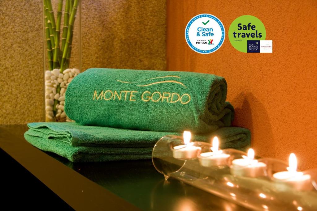 una pila de toallas y velas sobre una mesa en Monte Gordo Hotel Apartamentos & Spa en Monte Gordo