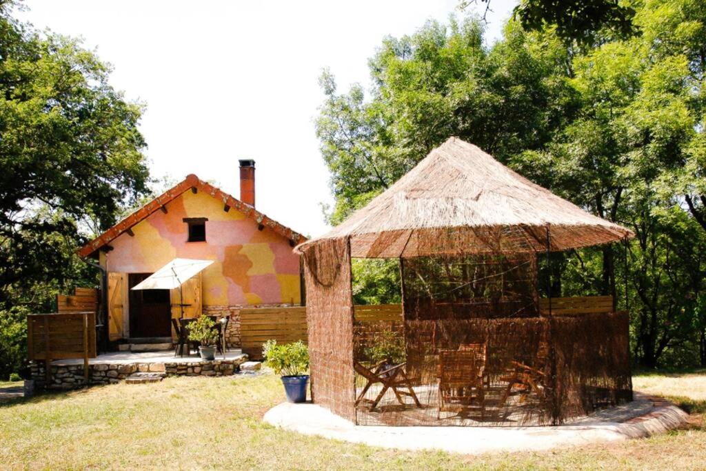 une petite maison avec toit de chaume dans une cour dans l'établissement La Tanière des druides, à Luzech