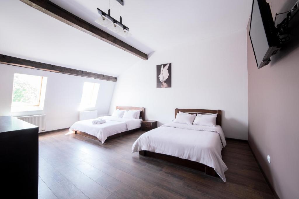 twee bedden in een kamer met witte muren en houten vloeren bij Апартаменти Центр Площа Митна in Lviv