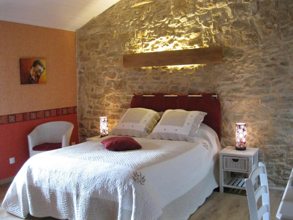 a bedroom with a large bed in a stone wall at Murmure des buis in Corveissiat