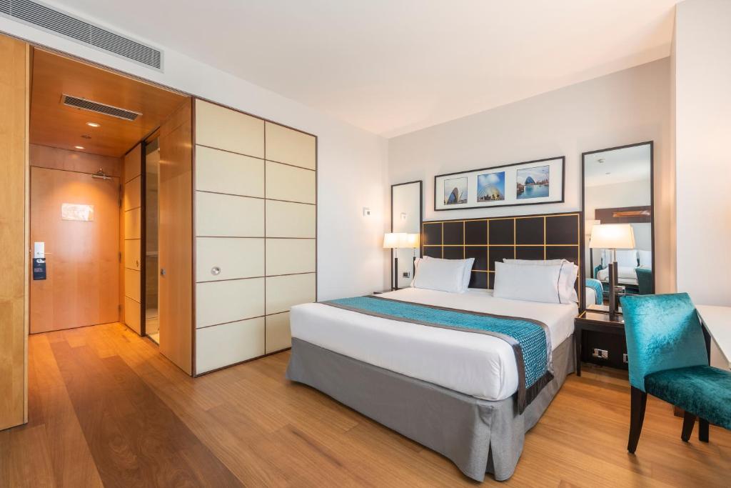 a bedroom with a bed and a desk and a chair at Eurostars Gran Valencia in Valencia