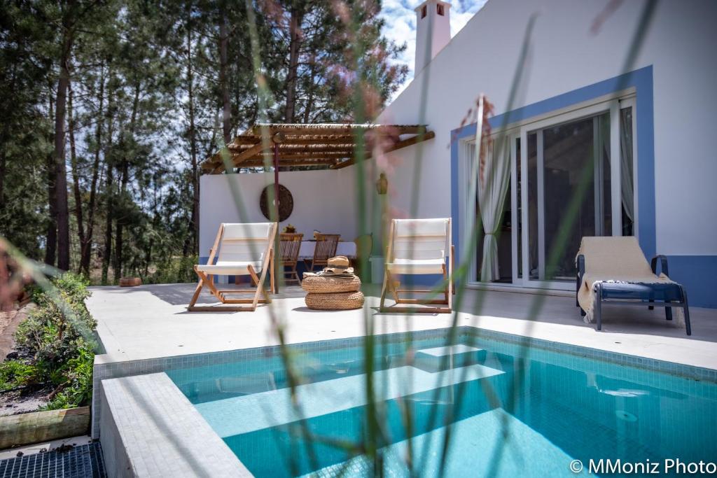 a house with a swimming pool and two chairs at Casas da Horta in Alcácer do Sal