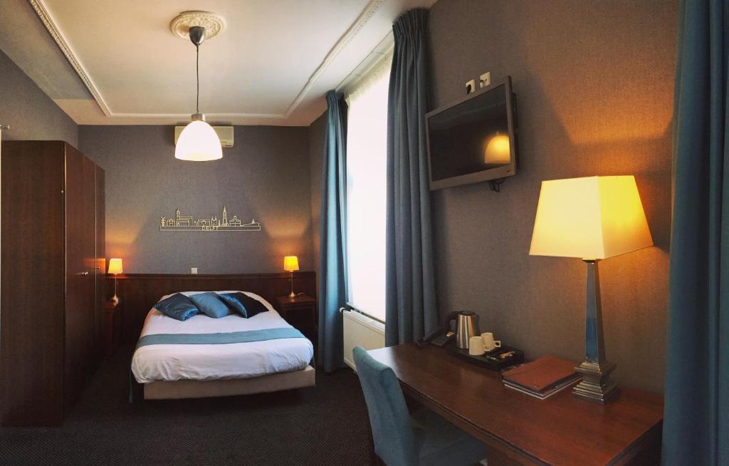 a bedroom with a bed and a desk with a lamp at Hotel Johannes Vermeer Delft in Delft