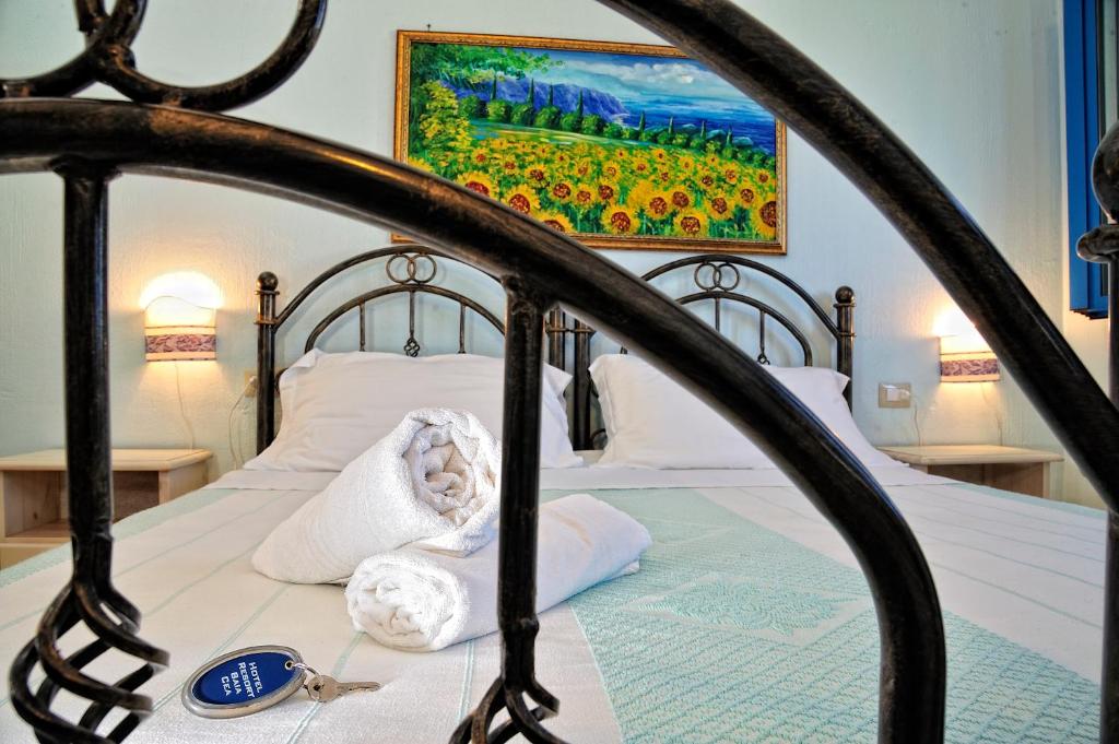 a bed with white pillows and a painting on the wall at Hotel Baia Cea in Bari Sardo