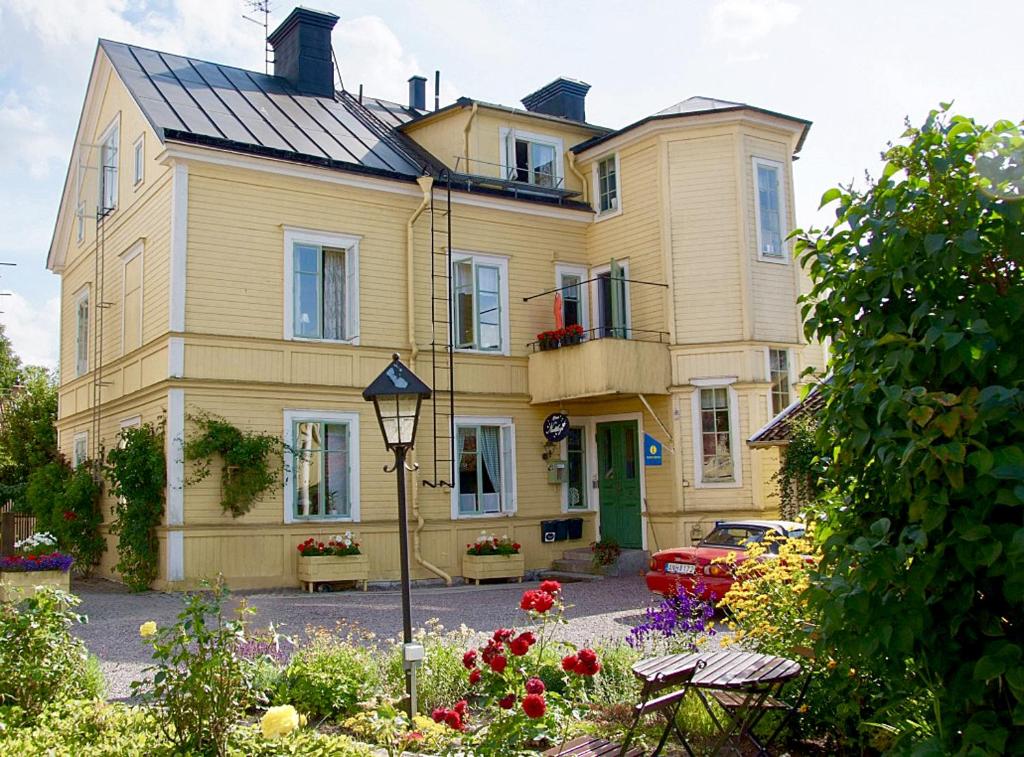 a large yellow house with flowers in front of it at 27ans Nattlogi in Vadstena