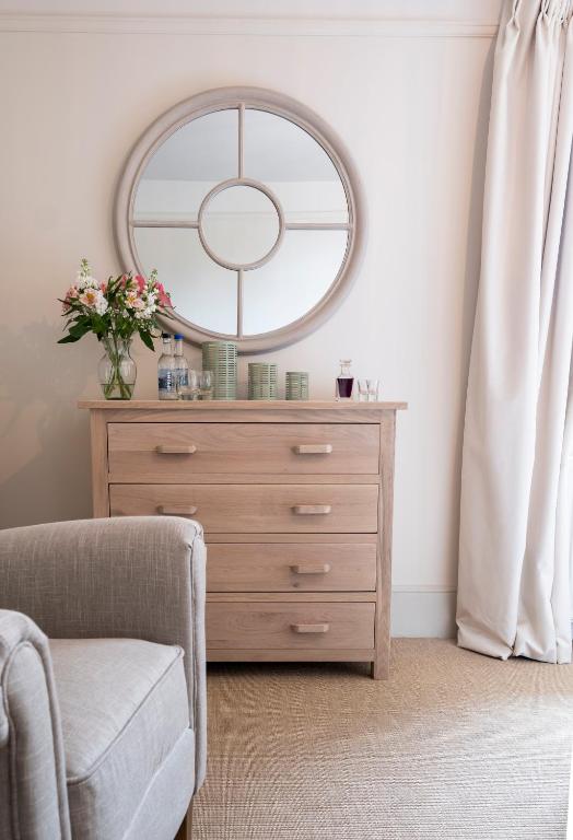 a bedroom with a dresser with a mirror and a chair at The Ship At Dunwich in Dunwich