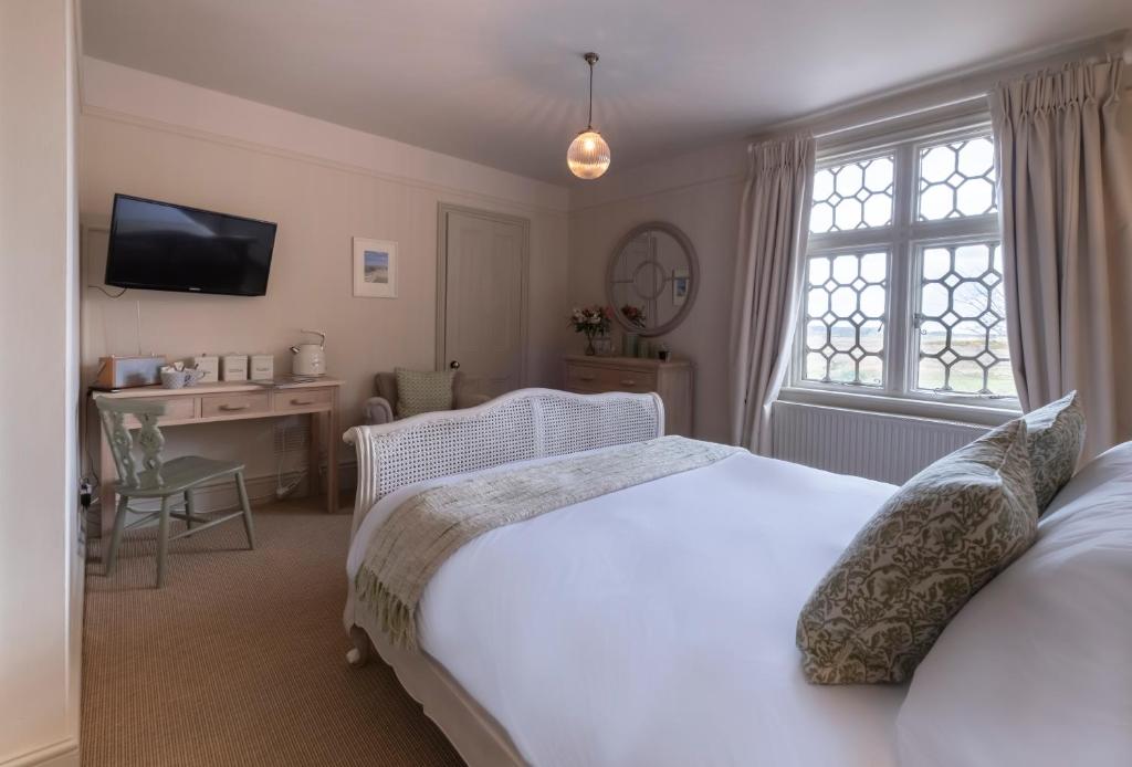 a bedroom with a bed and a desk and a television at The Ship At Dunwich in Dunwich