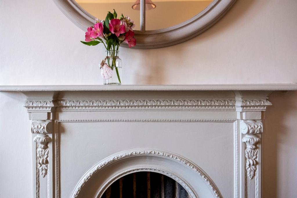 a mirror above a fireplace with a vase of flowers at The Ship At Dunwich in Dunwich