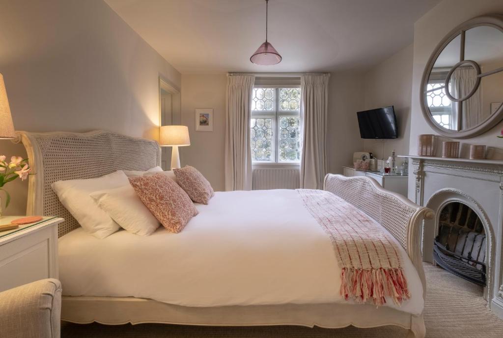 a bedroom with a large white bed with a fireplace at The Ship At Dunwich in Dunwich