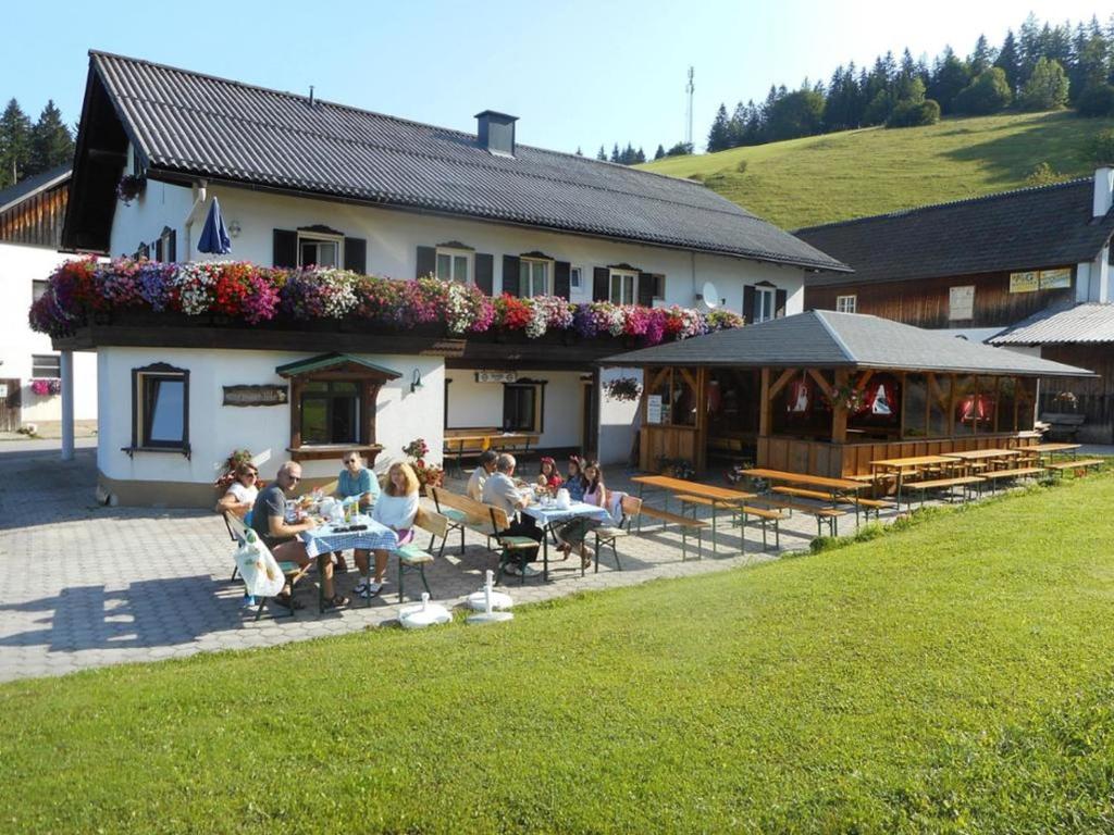 een groep mensen die aan tafels buiten een gebouw zitten bij Bio Bauernhof Moas in Lunz am See