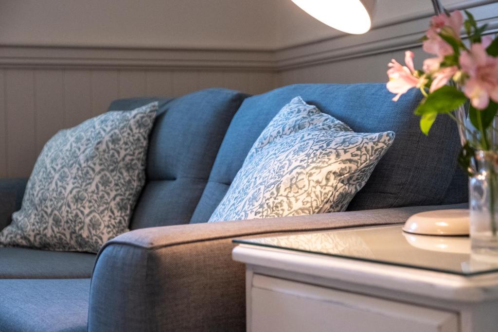 a blue couch with pillows on it next to a table at The Ship At Dunwich in Dunwich