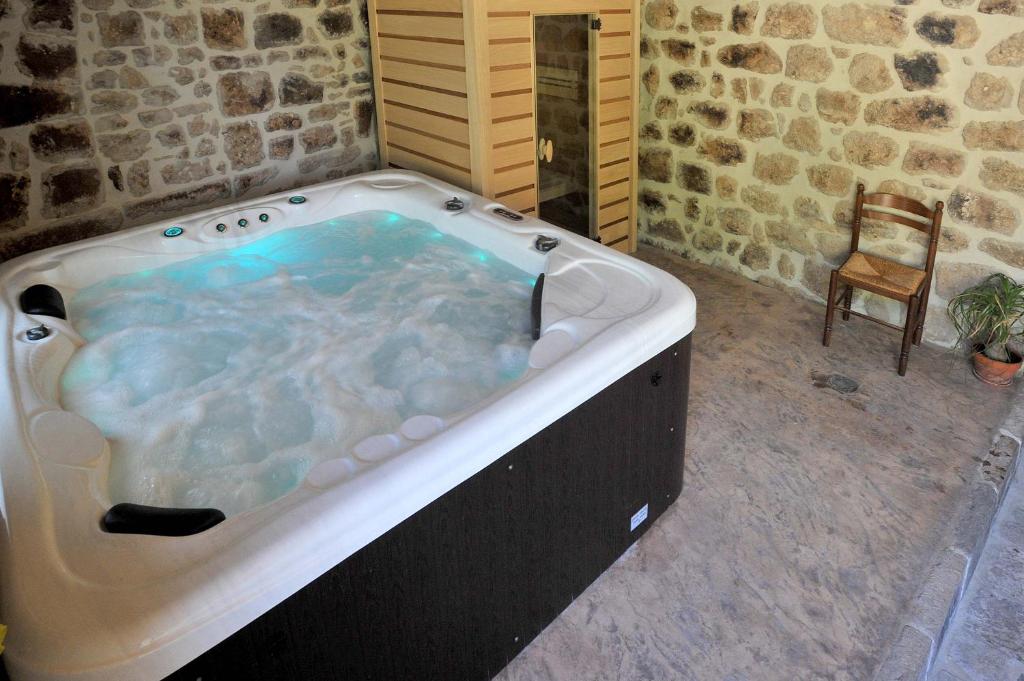 a large bath tub in a room with a chair at Chambre Comballe charmante avec jacuzzi in Sanilhac