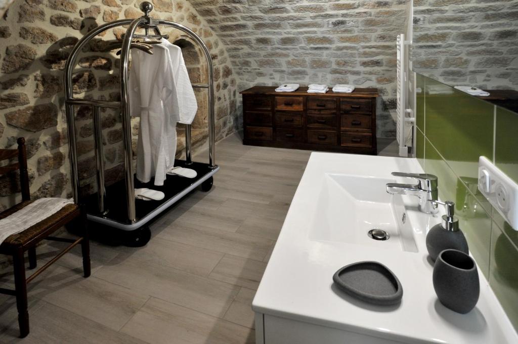 a bathroom with a white sink and a stone wall at Chambre Comballe charmante avec jacuzzi in Sanilhac
