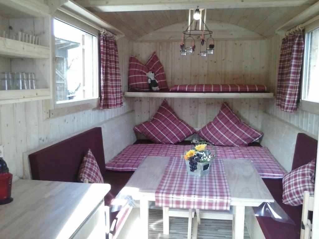ein kleines Zimmer mit einem Tisch und Bänken in einem Wohnwagen in der Unterkunft Schäferwagen auf dem Ferienhof Stark in Kelheimwinzer